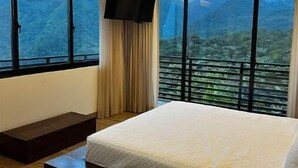 Un dormitorio con una cama grande, un televisor y vistas a un paisaje montañoso.