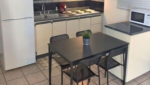 A compact kitchen with a dining table and chairs, a refrigerator, a microwave, and a sink.