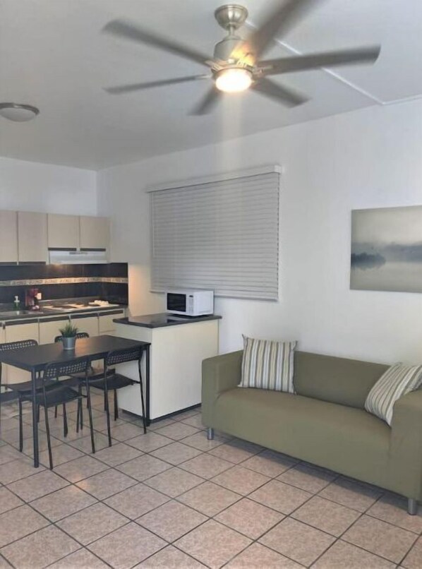 Un espacio habitable compacto con kitchenette, comedor y sofá.