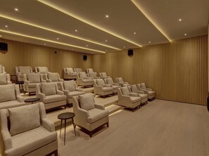 Una sala de cine con filas de asientos y una pantalla grande.