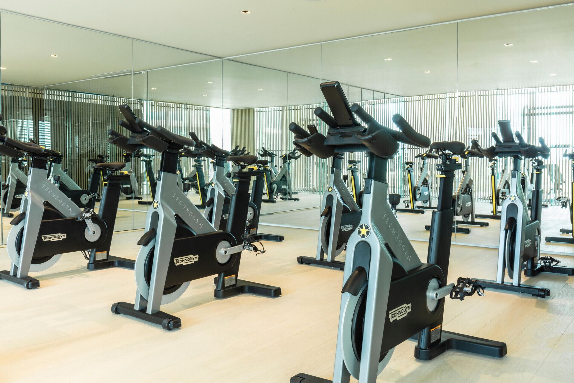 Uma academia com várias bicicletas ergométricas, um espelho grande e design de interiores moderno.
