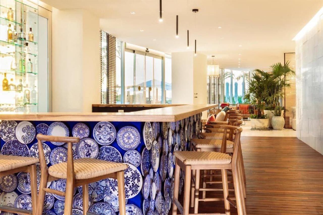 Eine Bar mit einer langen Theke, mehreren Hockern und einer Wand, die mit blauen und weißen Tellern dekoriert ist.