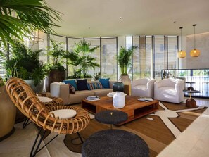 Un salon moderne avec un ensemble de canapés, une table basse et une grande fenêtre équipée de stores.