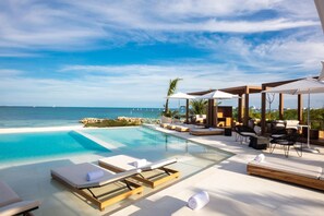A poolside area with lounge chairs and umbrellas, overlooking the ocean. - SLS Cancun (Cancun)
