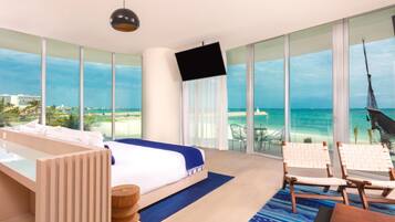 A hotel room with a bed, a TV, a balcony with a view of the beach, and a hammock.