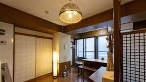 A traditional Japanese-style room with tatami flooring, a shoji screen, a wooden table, and a hanging light fixture. - Yoneyama 2F (Osaka)