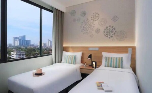 A hotel room with two beds, a nightstand, a window with a city view, and decorative wall patterns.