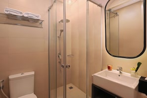 A bathroom with a glass-enclosed shower, a white sink, and a toilet.