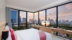 Ein modernes Hotelzimmer mit einem großen Bett, einem Fernseher und Blick auf die Stadt.