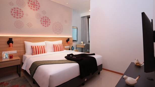 Ein modernes Hotelzimmer mit einem großen Bett, einem Schreibtisch und einem Fernseher.