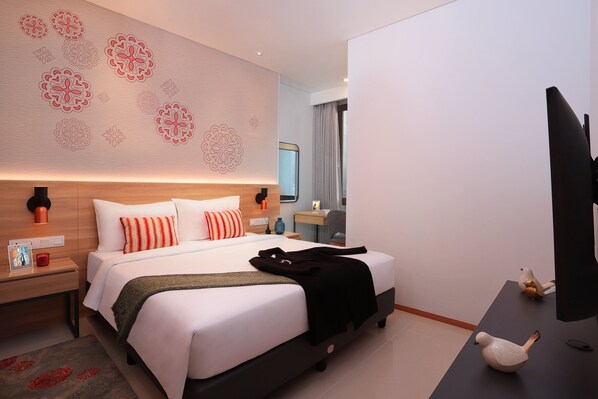A modern hotel room with a large bed, a desk, and a television.