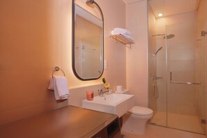 A bathroom with a sink, mirror, toilet, and glass-enclosed shower.