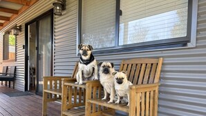 A wooden bench on a wooden deck in front of a building with metal siding and a window. - Bluelake Cottage Metung (Metung)