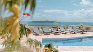 A poolside area with lounge chairs and a view of the sea. - Villa Magli (Christiansted)