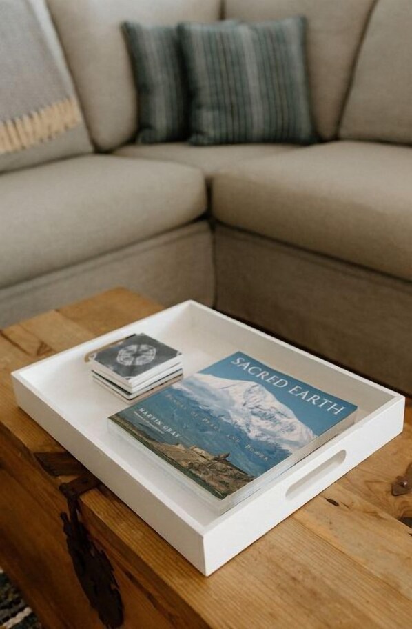 A white tray with a book titled "Sacred Earth" and a deck of cards on a wooden coffee table. - Villa Magli (Christiansted)