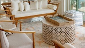 A spacious living area with a wooden ceiling, large windows, a white sofa, and a round wooden table. - Villa Magli (Christiansted)