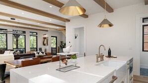 A modern kitchen with a large island, white cabinetry, and stainless steel appliances. - Swiss Chalet: Hot Tub, EV Charger, Lake Views (Grand Lake)