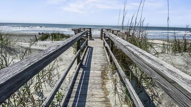 A wooden boardwalk leading to a beach with ocean views.