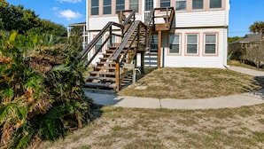 A two-story house with a wooden staircase leading to the front door.
