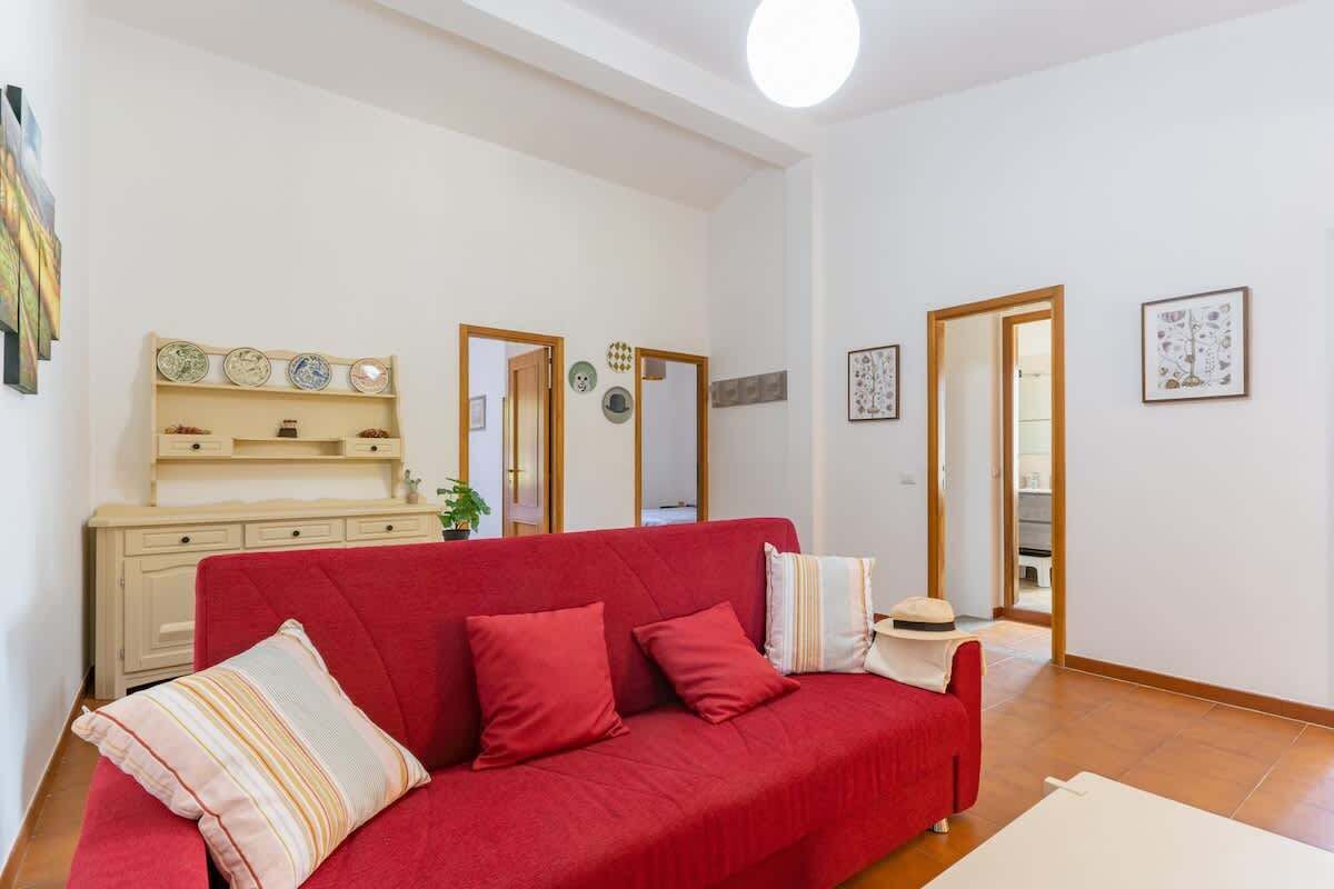 A living room with a red sofa, a wooden cabinet, and a mirror.