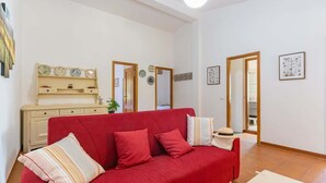 Una sala de estar con un sofá rojo, un mueble de madera y un espejo.