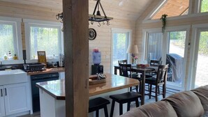 Ein gemütliches Blockhaus-Interieur mit einer Essgegend aus Holz, einer Küche mit weißen Schränken und einem großen Fenster.