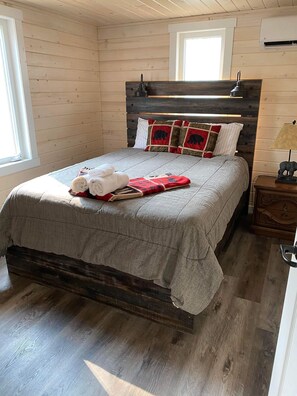 Ein gemütliches Zimmer mit einem hölzernen Bett, einem Nachttisch und einer Lampe.