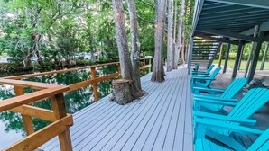 A wooden deck with a wooden railing, surrounded by trees and a body of water. - Waterfront Retreat + Kayaks - Extended Stay Deal (Spring Hill)