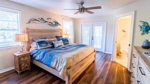 A bedroom with a wooden bed, a ceiling fan, and a nightstand with a lamp. - Waterfront Retreat + Kayaks - Extended Stay Deal (Spring Hill)