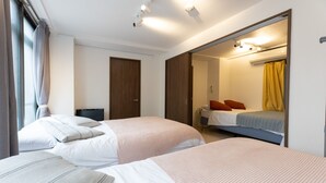A hotel room with two beds, a wardrobe, and a bathroom visible through an open door. - Yoneyama 4F (Osaka)