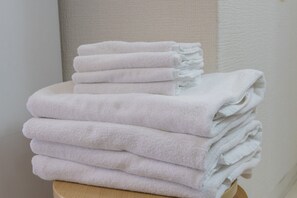 Toallas blancas apiladas sobre un taburete de madera.
