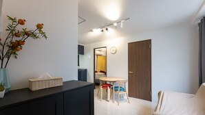A modern room with a dining area, a small kitchen, and a door leading to another room. - Yoneyama 4F (Osaka)