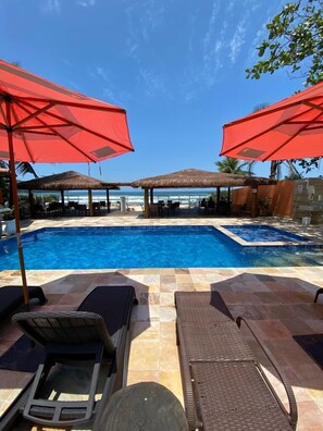 Una piscina al aire libre, sombrillas, sillones reclinables de piscina