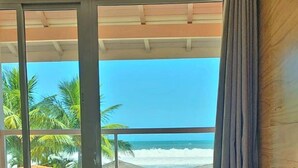 A bathroom with a large bathtub, a window with a view of the beach, and a curtain. - Pousada Maresias Beira Mar (São Sebastião)