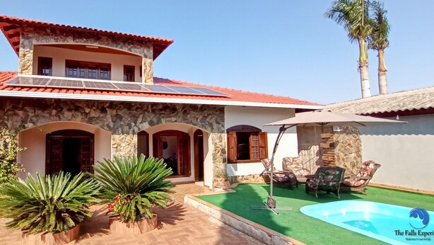 A two-story building with a stone facade, red-tiled roof, and a swimming pool. - Casa com Piscina e Churrasqueira (Foz do Iguaçu)