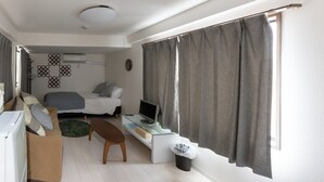 A compact hotel room with a bed, a desk with a computer, a sofa, and a small trash bin. - Yoneyama 5F (Osaka)