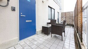 A blue door with a number plate, a small table with chairs, and a tiled floor. - Yoneyama 5F (Osaka)