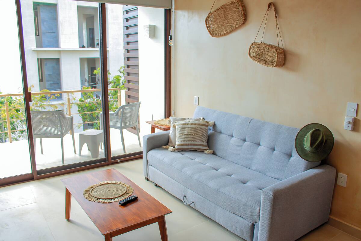 A living room with a sofa, a coffee table, and a balcony with chairs and a table.