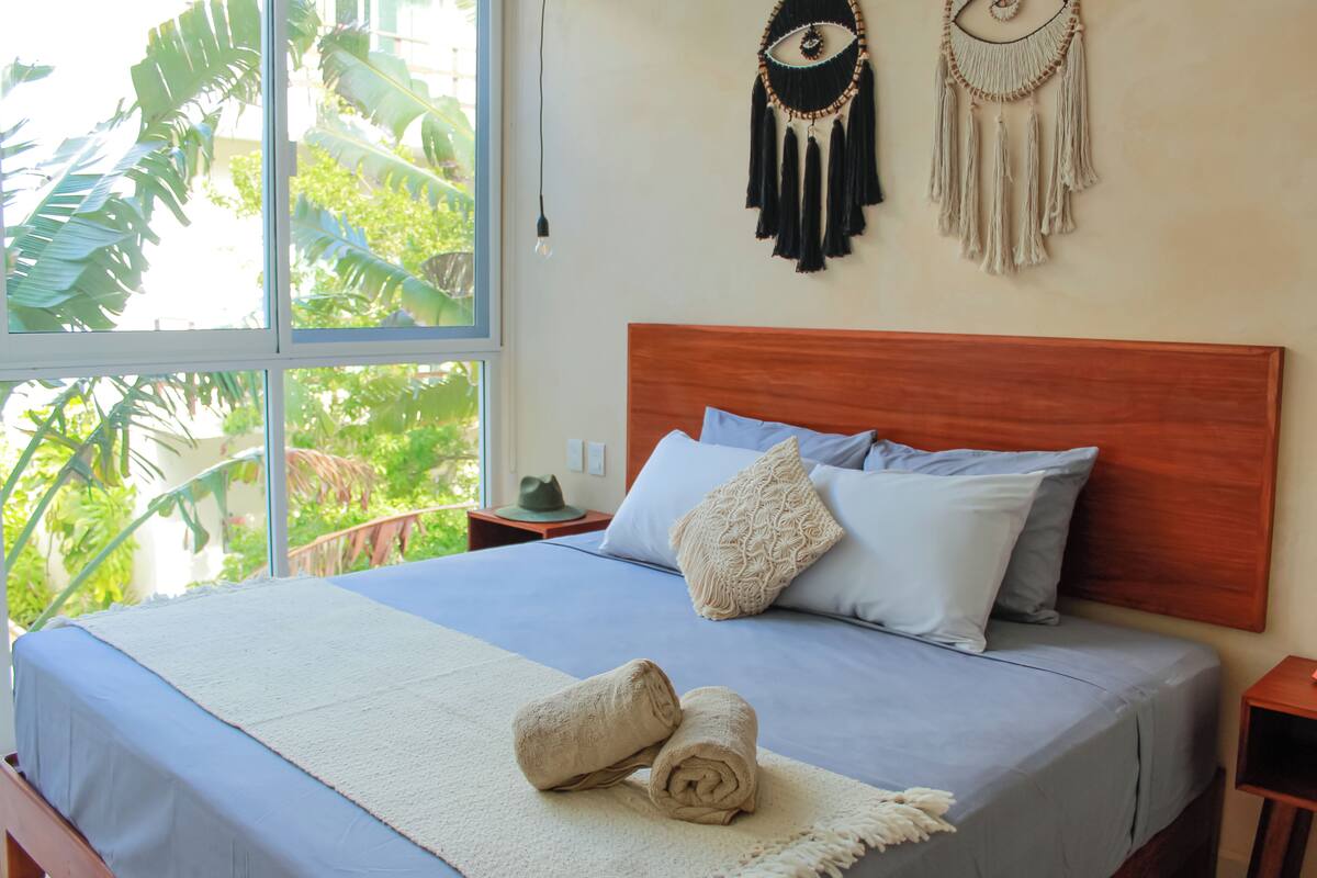 A neatly made bed with a blue bedspread, two pillows, and a white throw blanket. There are two wall decorations above the bed.