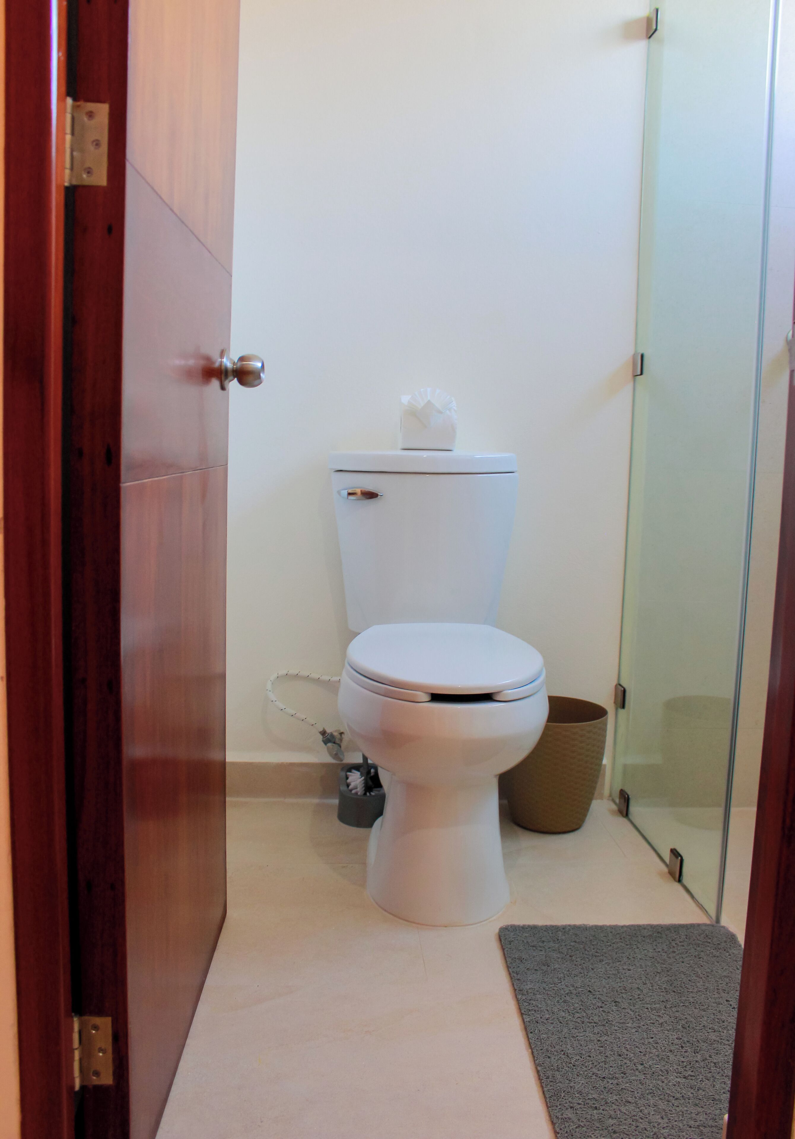 Ein Badezimmer mit Toilette, Mülleimer und Duschbereich.