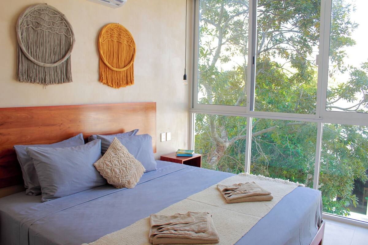 A bedroom with a large bed, a wooden headboard, and two wall decorations.