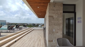 Eine Dachterrasse mit Liegestühlen, einem Pool und einer Steinmauer.