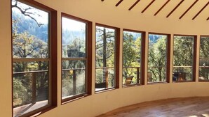 Una habitación con amplios ventanales que ofrecen vistas a árboles y montañas.