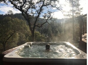 A hot tub in a natural setting with trees and a forest in the background. - Stunning Roundhouse, Waterfall, Hot Tub & Views (Grass Valley)