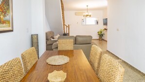 Un comedor con una mesa de madera, sillas tejidas y un cuenco grande tejido.