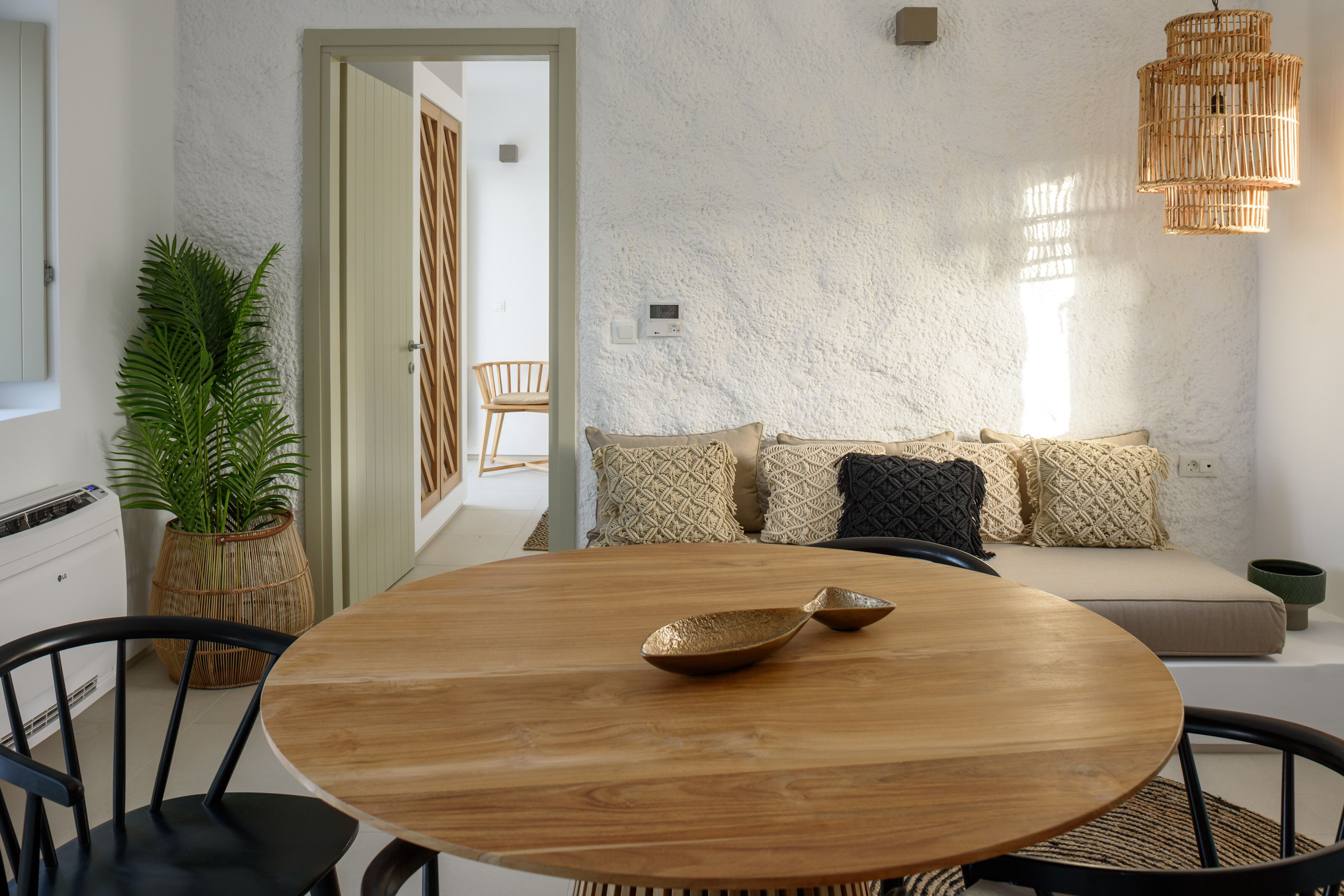 Un comedor con una mesa redonda de madera, sillas negras y una cesta tejida.