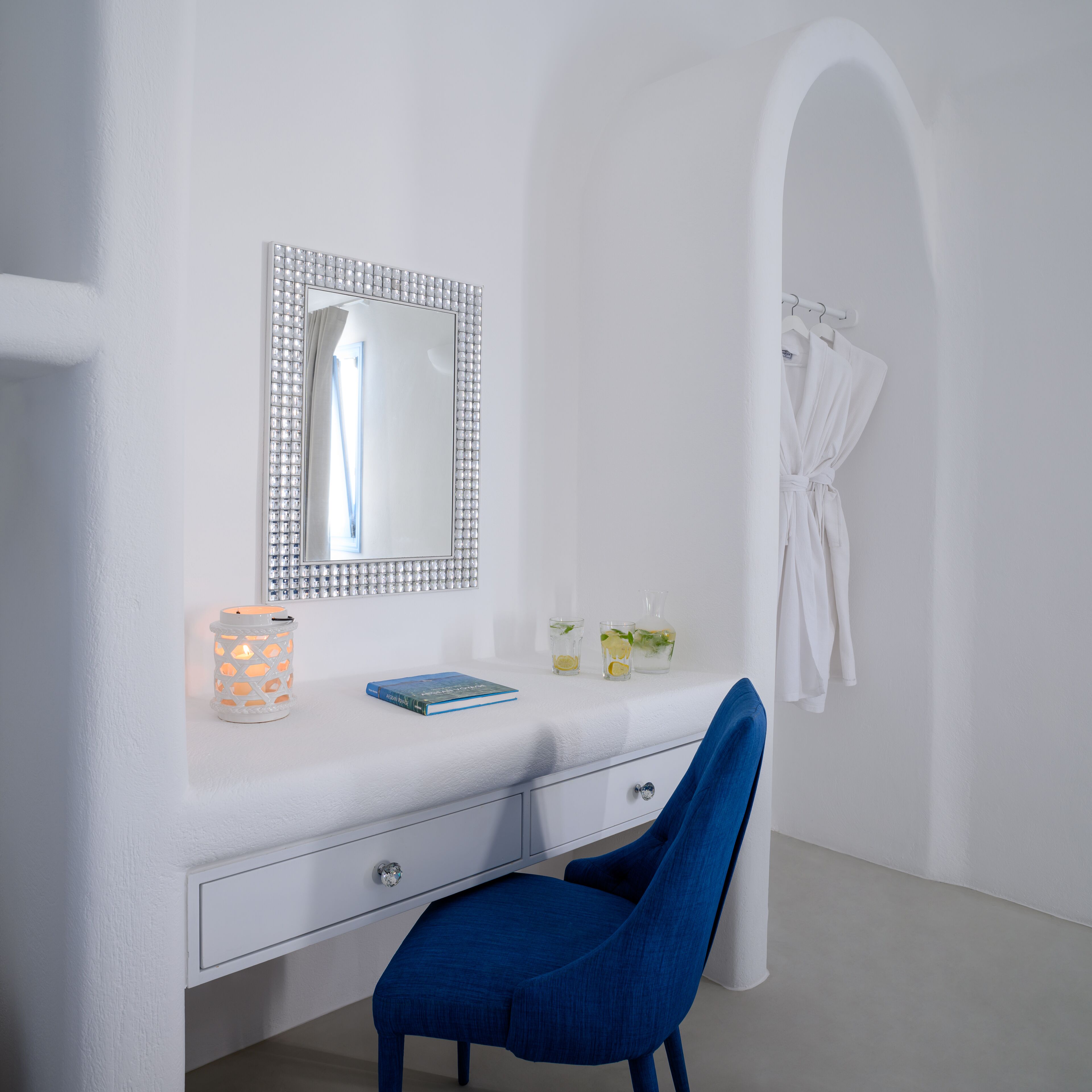 A white vanity with a mirror, a book, and a candle.