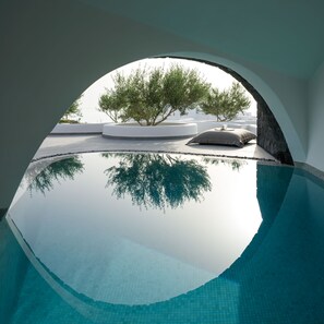 Vista chiara di una piscina con il riflesso di alberi e un edificio bianco sullo sfondo.
