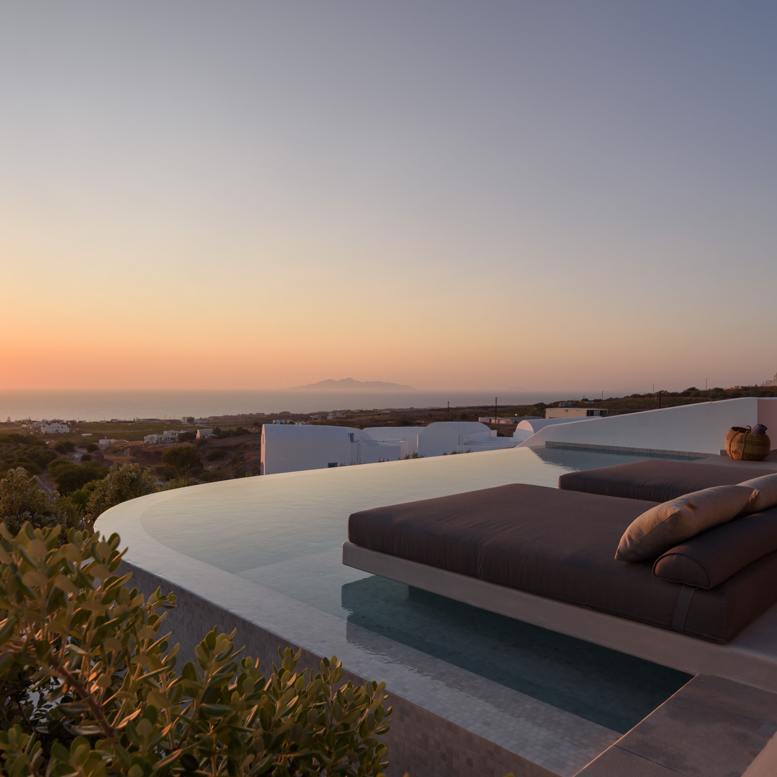 Une piscine à débordement moderne offrant une vue sur la mer et les montagnes lointaines.