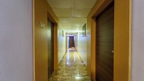 Un corridoio con porte in legno, pavimento in marmo e soffitto con illuminazione incassata.